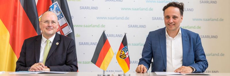 Der Präsident des BSI, Arne Schönbohm, (links) und der saarländische CIO, Ammar Alkassar, (rechts) unterzeichnen die Kooperationsvereinbarung
