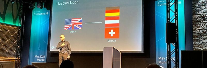 Tribe29-Gründer und -CEO Mathias Kettner eröffnete am 03. Mai 2022 die 8. Checkmk Conference in München – und wies mit einem Augenzwinkern auf die Simultanübersetzungen der in Englisch gehaltenen Konferenz ins Deutsche, Österreichische und Schweizerische hin.