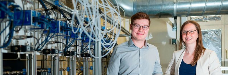 Dennis Arendes, Mitarbeiter am Lehrstuhl von Prof. Andreas Schütze (li.), und Dr. Caroline Schultealbert (3S GmbH) vor einer Gasmischanlage, mit deren Hilfe hochsensitive Gas-Sensoren kalibriert werden, wie sie auf der Hannover Messe vorgestellt werden.