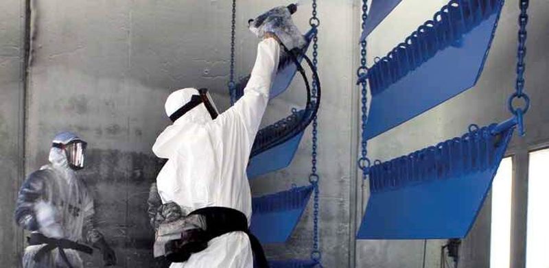 Semi finished parts are being spray painted in a factory.