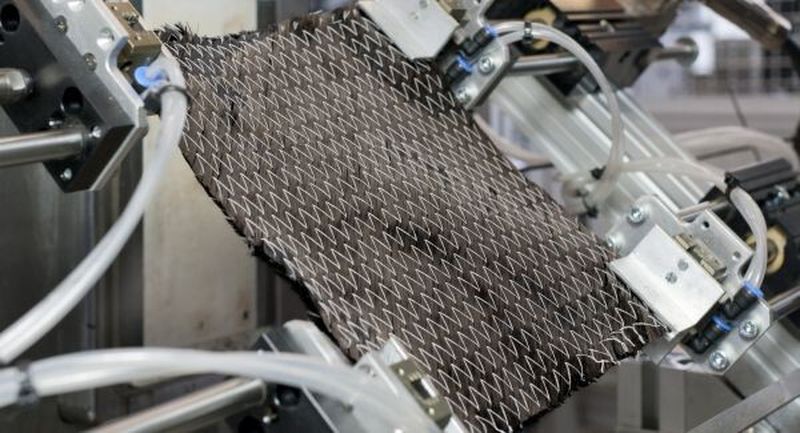 Das trockene, biegeschlaffe Gelege aus Kohlenstofffasern wird ins Werkzeug einer Spritzgießmaschine gelegt.