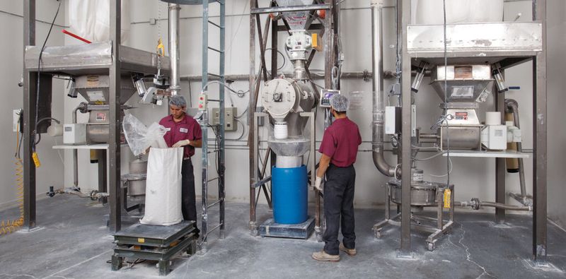 From each bulk bag unloader, particles are micronized in a vortex mill (at floor level), pneumatically conveyed into the product collector, and screened in the centrifugal sifter below it.