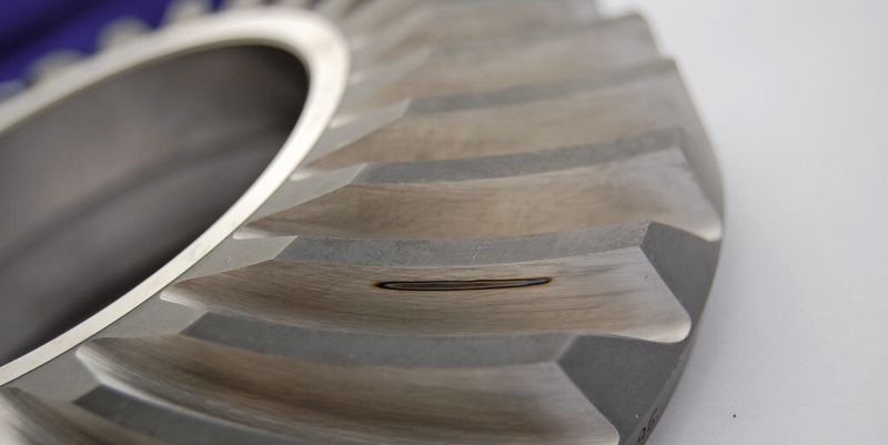 Bild 1: Die ISO 14104 verlangt, dass der Zustand des Ätzbades beim Nitalätzverfahren durch Referenzteile überprüft wird. Nun wurde ein Verfahren entwickelt, mit einem Laser definierte Ersatzfehler, wie beispielsweise eine strichförmige Marke auf der Zahnunterseite eines Getriebeteiles, in die Schleifbrandmaster einzubringen.