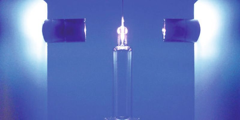 Eine Metallnadel wird in eine Glasspritze verklebt: Der Klebstoff wird mit zwei LED-Köpfen ausgehärtet.