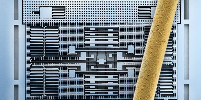 Bausteine für die vernetzte Welt: Das Bild eines Rasterelektronenmikroskops (REM) zeigt die feinen geätzten Silizium-Strukturen eines Beschleunigungssensors von Bosch. Zum Größenvergleich liegt ein menschliches Haar auf der Struktur. Die Silizium-Strukturen in der Mitte des Chips messen die Beschleunigung oder Neigung in allen drei Raumrichtungen. Die einzelnen „Balken“ sind rund 2 µm breit und 20 µm hoch. Das Haar ist im Vergleich rund 90 µm dick.