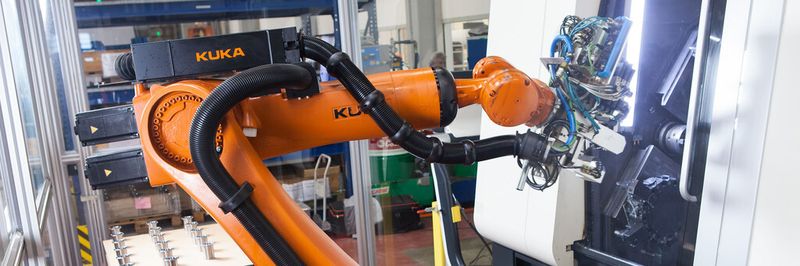 Der Roboter bestückt den Drehautomaten, der aus Sägeabschnitten die Roboterkomponenten fertigt.