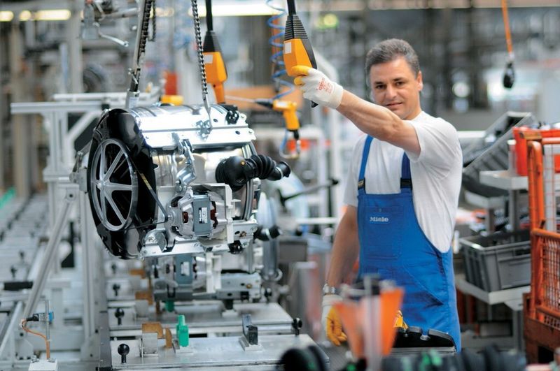 Waschmaschinen-Produktion bei Miele in Gütersloh. Über 16.500 Menschen arbeiten weltweit für das Familienunternehmen, über 60 % in Deutschland. Die Verbundenheit zum Unternehmen ist groß, die Fluktuation liegt bei weit unter 1 %.