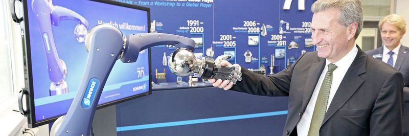 Günther Oettinger beim Handschlag mit dem Leichtbauarm von Schunk. In der Fabrik der Zukunft werden Mensch und Roboter Hand in Hand arbeiten.