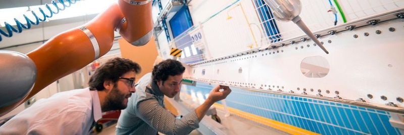 José Navarro, IDPSA, und José Saenz vom Fraunhofer IFF prüfen, wie Valeri das Dichtmittel auf ein Flugzeugbauteil aufgebracht hat.