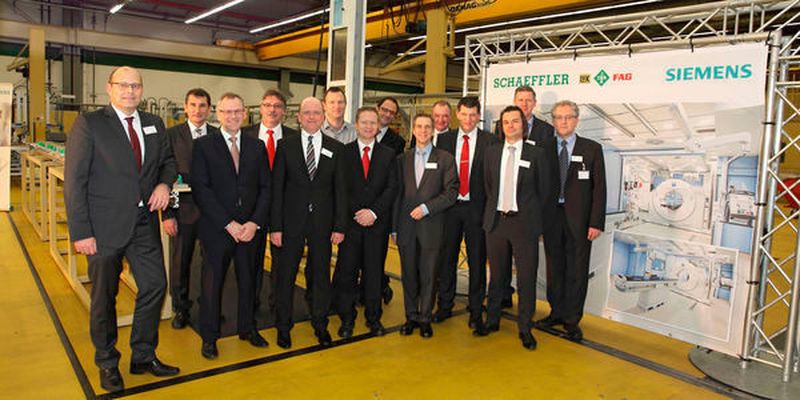 Kleine Feierstunde in großer Runde: Anlässlich der Auslieferung des 100. Fahrsystems für Computertomographen haben sich die Pojektverantwortlichen von Siemens und Schaeffler Lineartechnik im Werk Homburg/Saar eingefunden.