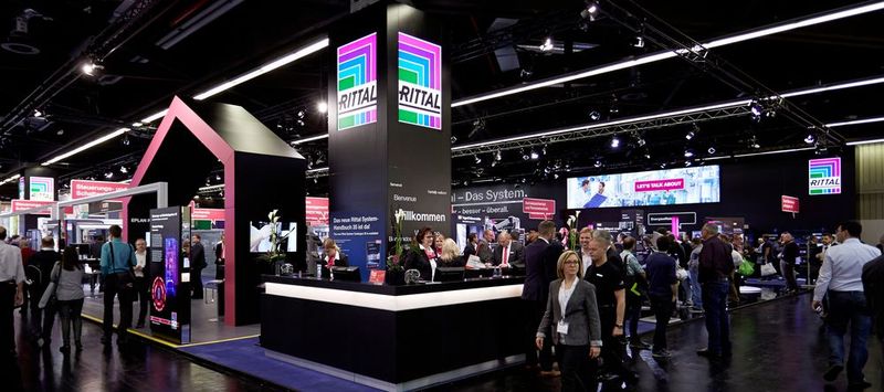 Der Lösungsanbieter für die Wertschöpfungskette im Steuerungs- und Schaltanlagenbau – so präsentiert sich Rittal auf der SPS IPC Drives in Nürnberg. Highlight ist die Vorstellung des neuen Großschranksystems VX25 - dem ersten Schaltschranksystem, das vollständig entlang den Anforderungen nach erhöhter Produktivität und denen von Industrie 4.0 entwickelt wurde.  Im Zentrum des 1120 m² großen Rittal Messestandes können sich Besucher auf einer Highlight-Fläche mit dem neuen Schranksystem vertraut machen. An verschiedenen Inseln zeigt der Hersteller Details zu den neuen technischen Features. Praktische Workshops machen dabei die Vorteile des VX25 erfahrbar. Demonstriert werden etwa die Montage von Türen und Flachteilen, der Einbau von Chassis, das Nachrüsten des 180°-Scharniers und Komfortgriffs sowie die Anreihung von Schränken.  Rittal auf der SPS IPC Drives 2018: Halle 3.C, Stand 430 (Bild: Rittal)