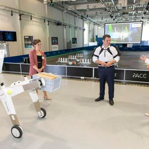 Bundesarbeitsminister Heil am Fraunhofer-Institut für Materialfluss und Logistik IML mit körperentlastendem Exoskelett, das man dort testet. Im Vordergrund der AMR „evoBOT“.(Bild:  Fraunhofer IML)