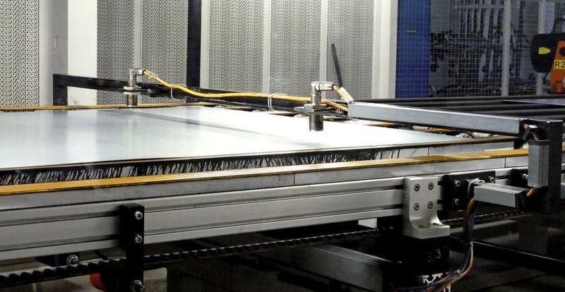 Zur Sicherheit wird die einzelne Platine auf dem Feeder nochmals gemessen, damit auch wirklich nur ein Blech in das Pressenwerkzeug gelangt. Diesmal ist es eine zweiseitig berührungslose Doppelblechkontrolle mit Sender oben und Empfänger unten: An zwei Stellen wird die Platine zweiseitig berührungslos gemessen... Bild: Kuhn (Archiv: Vogel Business Media)