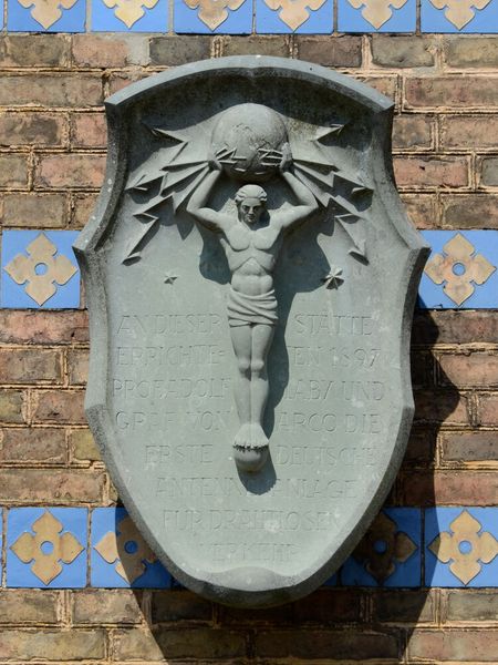 Die Atlasplatte an der Heilandskirche mit der Inschrift zu Ehren von Arco und Slaby. (Bild: Atlasplatte am Campanile der Heilandskirche in Sacrow / Musil / CC BY-SA)