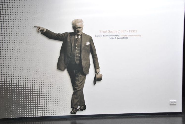 „Hier geht's lang!“: Der Firmengründer Ernst Sachs weist den Weg in die Ausstellung, die in dem einstigen Industriebau aus den sechziger Jahren ein passendes Flair findet. (Foto: Dominsky)