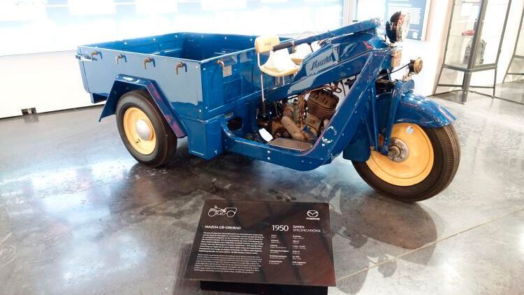 Das Mazda-Go war das erste Fahrzeug von Mazda – ein dreirädriger, offener oder geschlossener Pritschenwagen, der ab 1931 produziert wurde. Das Vorderrad hing an einer gefederten Gabel wie bei einem Motorrad und wurde mit einer Lenkstange gelenkt. Angetrieben wurde das Go von einem luftgekühlten Einzylindermotor mit verblocktem Dreiganggetriebe, der zu Beginn bei 482 Kubikzentimetern 6,9 kW/9,4 PS leistete.  (Bild: Dominsky/»kfz-betrieb«)