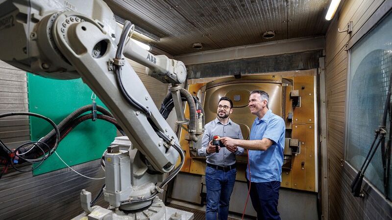 Daniel Kohn (li.) und Jürgen Böhringer, beide Diehl Aviation, vor der Roboteranlage für die automatisierte Reinigung von Presswerkzeugen.