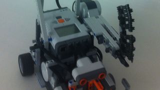 Unser Roboter ist ein kleines Polizeiauto, das mit 2 Fahrmotoren sowie  einer Pistole ausgerüstet  ist.  Zur Orientierung kommen ein Kompasssensor, zwei Kollisionssensoren sowie ein Lichtsensor zum Einsatz. (itemis)