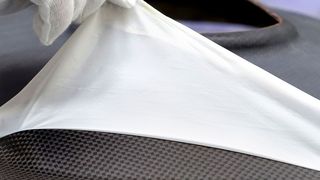 Händischer Abzugsvorgang einer Flexplas-Trenn- und Schutzfolie, entwickelt vom Fraunhofer-Institut für Fertigungstechnik und Angewandte Materialforschung (IFAM), von einem kontaminationsfreien CFK-Bauteil nach dessen Aushärtung in der Heizpresse. (Fraunhofer IFAM)