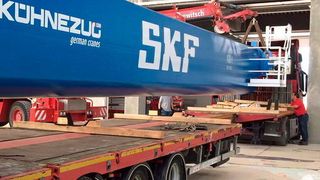 Wie durch ein Nadelöhr: Ein Tieflader fädelt einen fast 20 m langen und mehr als 15 t schweren Querträger für den Hauptkran in das neue Prüfzentrum ein. (SKF)
