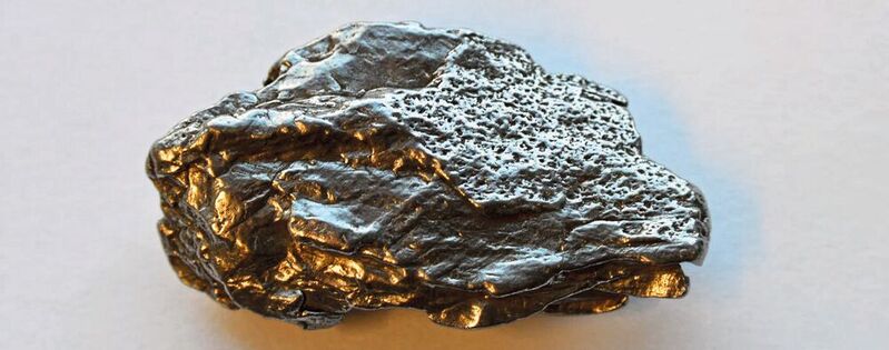 Ein kleines Fragment des Campo-del-Cielo-Eisenmeteoriten. Dieselbe intensive Hitze, die den Meteoriten teilweise aufgeschmolzen und so die hier sichtbare glatte Oberfläche erzeugt hat, hätte auch Eisen verdampft und abgetragen, wobei winzige, nanometergroße Partikel entstanden wären. Diese Partikel könnten als Katalysatoren für die Herstellung der chemischen Bausteine des Lebens auf der frühen Erde gedient haben. 