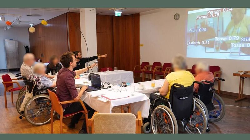 Forschende, Bewohner:innen und Pﬂegepersonen gestalten gemeinsam den Einsatz robotischer Technologien. Im Bild diskutieren sie ein Computer-Vision-System, das Objekte in der Umgebung erkennt und auf einem Bildschirm sichtbar macht, und tauschen sich über erwünschte Anwendungen, technische sowie ethische Grenzen im Pﬂegealltag aus. (Bild: Helena A. Frijns / Caring Robots )