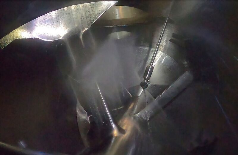 Rotating flat fan cleaning nozzle in a 10.000 l Lödige Ploughshare-Mixer in operation. (Lödige Process Technology)