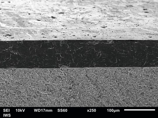 Ultradicke ta-C Schicht von etwa 100 µm Schichtdicke nach Glättung. Schrägansicht auf die Bruchfläche im Rasterelektronenmikroskop. Im Gegensatz zu «normalen» diamantartigen Kohlenstoffschichten mit wenigen Mikrometern Dicke, hält diese ta-C-Schicht auch lokalen Überlastungen stand, z. B. abrasive Staub- oder Sandpartikel.(Bild:  Fraunhofer IWS)