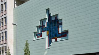 Bei der Fassadensanierung eines Gymnasiums in Koblenz rahmt die FC Fassade das kunstvolle Fliesenmosaik ein. (Bild: Kalzip GmbH)