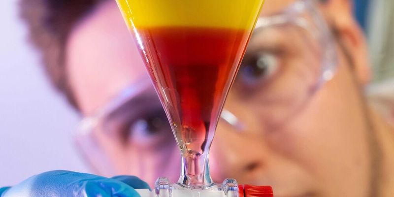 Doktorand Nikolai Löhr ist Erstautor der Studie. Er zeigt Anthrachinon-Verbindungen, die ihre Farbe und Löslichkeit verändern, je nach pH-Wert der Umgebung. Oben: unter sauren Bedingungen in organischer Lösung. Unten: in alkalischer, wässriger Lösung.(Bild:  Jens Meyer/Uni Jena)