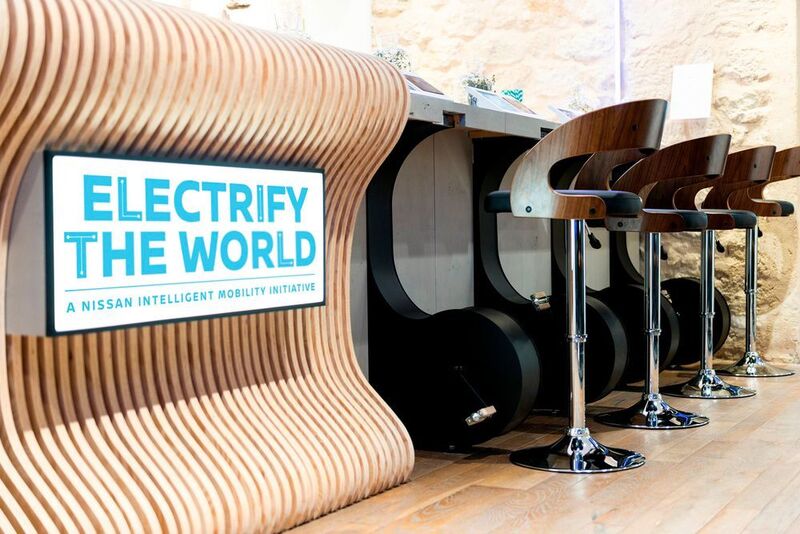Besucher nehmen im Café auf einem „Ergometer-Barhocker“ Platz. Durch kräftiges Treten der Pedale wird Strom erzeugt, der in ein x-Storage-Speichermodul eingespeist wird.  (Nissan)