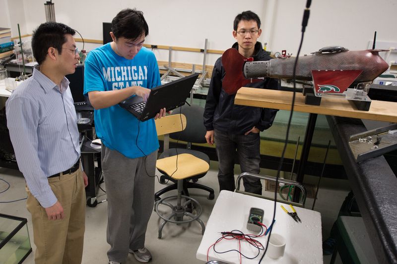 Die Doktoranten Feitian Zhang (M.) und Jianxun Wang (r.) bei der Arbeit an dem Roboter-Fisch im Labor von Professor Xiaobo Tan (l.). (Michigan State University/G.L. Kohuth)