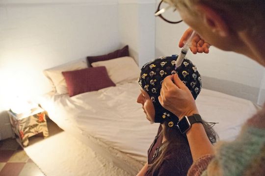 Zur Messung der Hirnströme, aus der die Forschenden das persönliche Schlafprofil ableiten können, wird eine Probandin bei sich zu Hause mit Elektroden versehen, sodass sie in gewohnter Umgebung schlafen kann.  (Bild:  © zvg)