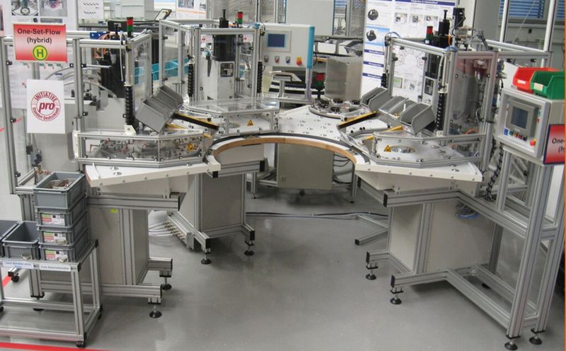 „One-set-flow-Montage“ - Wanderdrehteller (vergleiche Lotter [2]). Die Arbeitsplätze sind in Halbkreisform angeordnet. Die Mitarbeiter transportieren einen Satz von Teilen auf einem runden Mehrfach-Werkstückträger. Vorteile: Nebenzeiten fallen pro Satz nur einmal an. (Bild: Fraunhofer-IAO)