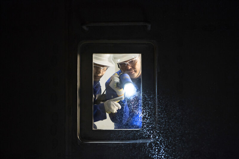 Zwei BASF-Mitarbeiter bei der Produktprüfung durch das Kontrollfenster eines Wirbelschichttrockners im BASF-Flockungsmittelwerk in Nanjing/China (Bild: BASF / Detlef W. Schmalow)