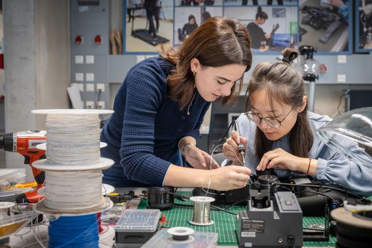 Dr. Xiaohui Zhang (rechts) und Dr. Enrica Tricomi justieren den Motor, der den Exosuit antreibt.(Bild:  TUM)