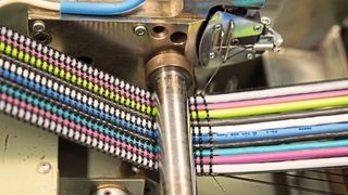 Gewebebandkabel: Während elektrische Leitungen, dünne Rundkabel oder Schläuche wie Kettfäden in Längsrichtung verlaufen, lassen textile Garne quer dazu ein Gewebe entstehen. (TKD Kabel)