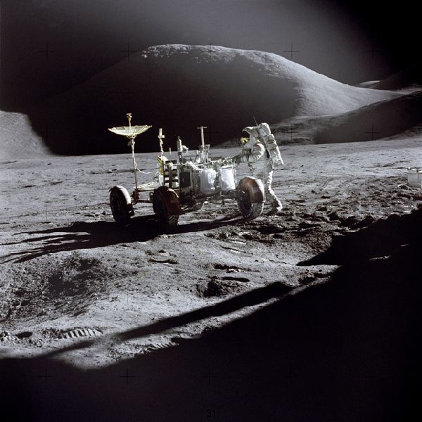 Astronaut James B. Irwin bei Arbeiten am Lunar Roving Vehicle während des ersten Mondausflugs der Apollo-15-Mission. Im Vordergrund ist der Schatten der Mondlandefähre „Falcon“ zu sehen. Das Bild zeigt den Nordwesten des Landplatzes mit Mount Hadley im Hintergrund und wurde von Kommandant David R. Scott aufgenommen. (Bild: NASA)