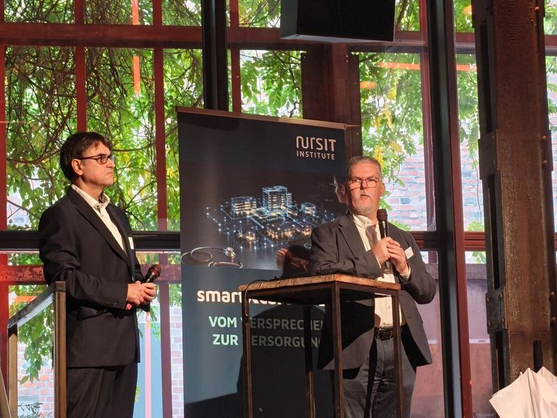Die Geschäftsführer des NursIT Institute, Stoyan Halkaliev (v. l.) und Heiko Mania, begrüßen die Besucherinnen und Besucher und geben einen Einblick in die Geschichte des Unternehmens: NursIT wurde vor elf Jahren gegründet, der Veranstaltungsname smartXcare besteht dagegen seit fünf Jahren. Mania erklärte: „Das X steht für die unzähligen Themen im Gesundheitsbereich – von der Pflege und den Kliniken über Arztpraxen, Pharma-Unternehmen und Apotheken bis hin zu Krankenversicherungen, Medizintechnik und Digital Health.“ (Bild: © Serina Sonsalla)