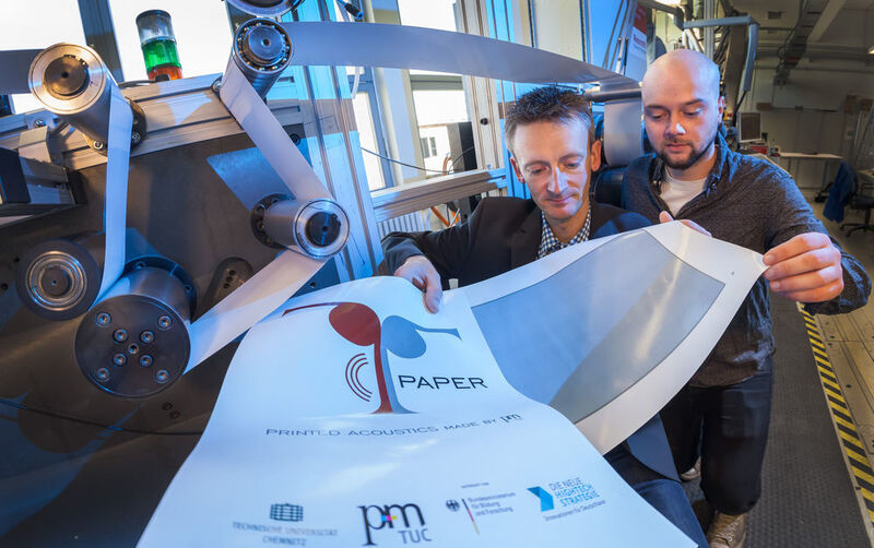 Dr. Georg Schmidt (l.) und Student Robert Eland kontrollieren an einer Rolle-zu-Rolle-Druckmaschine im Labor der Professur Printmedientechnik die Qualität eines Probedruckes. (TU Chemnitz/Uwe Meinhold)