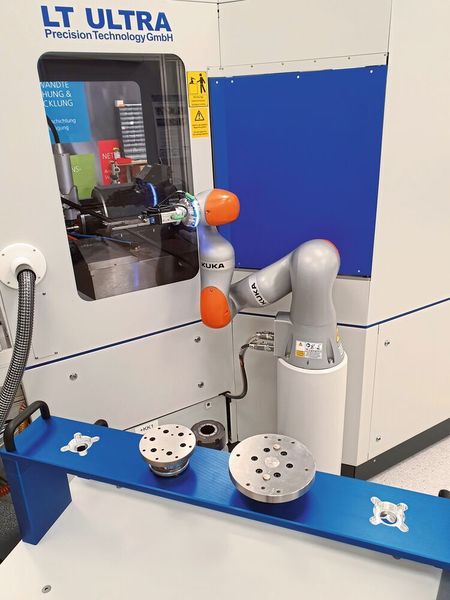 Der Roboterarm holt vorbereitete Werkstücke vom Palettenwagen im Vordergrund und macht den automatischen Werkstückwechsel. (Kuka / RhySearch)