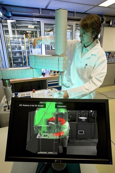 Auf dem unteren Bildschirm ist ein sonst nicht sichtbarer Lichtkäfig eingeblendet. Der Roboter unterbricht seine Bewegung, sobald ein Mensch in den Arbeitsraum eindringt. (Bild: Fraunhofer)