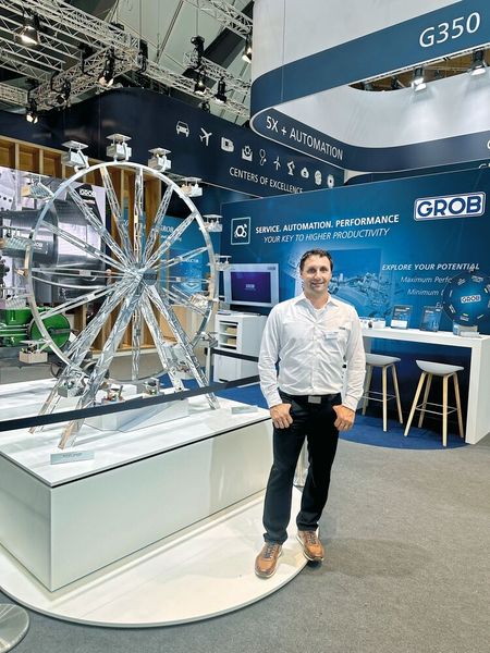 Sebastian Schön, sur le stand de GROB-WERKE devant la grande roue réalisée par les apprentis de l'entreprise spécialement pour l'AMB 2026. (Source : Margaux Pontieu)