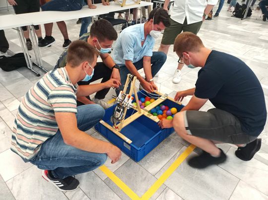 (Letzte Vorbereitungen: Das Team hat als Lösung eine dreieckförmige, gelenkig verbundene Kippvorrichtung entwickelt. Bildquelle: Schunk)