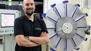 Verbundwerkstoffspezialist Dr. Marcel Bücker vor der laufenden Produktionsanlage, mit deren Hilfe die Fertigung von Speichenrädern aus Verbundwerkstoffen optimiert werden kann. Hier befindet man sich im letzten Schritt, bei dem der Außenring gewickelt wird. (Evolime)