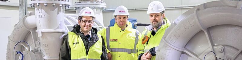 Tobias Boeckh, Geschäftsführer Continental Industrie, Projektleiter Niklas Hense von Revis bioenergy und Jens Steller, Interimsbetriebsleiter der Biogasanlage (v. links) neben den beiden redundant ausgeführten großen Industriegebläsen von Continental Industrie in der Biogasaufbereitungsanlage. Sie sorgen für die nötige Stabilität im nachgeschalteten Reinigungs- und Trennverfahren.(Bild:  Continental Industrie GmbH)