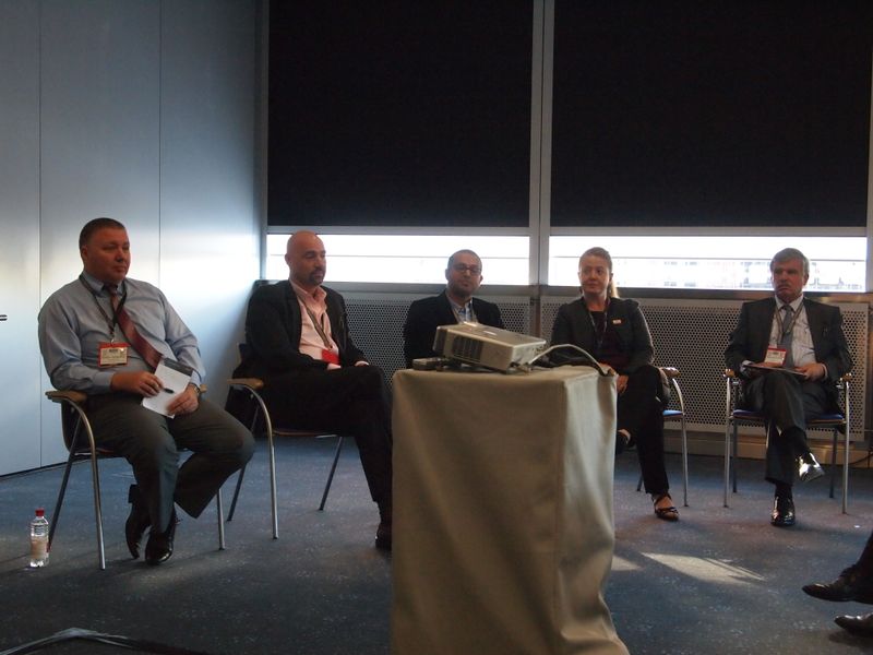 Roundtable der Archivierungsspezialisten auf dem Tape Summit. An der Location sollte man noch arbeiten. Die Pläne der fünf Firmen sind allerdings hochgesteckt: Wenn man die SSD-Technik mit dem Tape verheiratet, dann könnte man eigentlich auf die Festplatte verzichten.  Von links: Gabriel Chaher, Quantum; Molly Rector, SpectraLogic; Harry Weik, Grau Data. (Rainer Graefen)