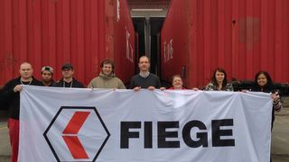 Marc Baumgarte, Fiege-Regionaldirektor Südwest (Mitte), mit May Roa-Engel (ganz rechts) und weiteren Mitarbeiterinnen und Mitarbeitern von Fiege Bürstadt und Fiege Worms vor den 40-Fuß-Containern mit Hilfsgütern. (Bild: Fiege)