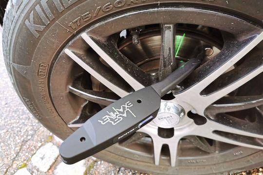 Ein Magnet fixiert den Examiner in der korrekten Messposition auf der Bremsscheibe. Der schlanke Messfuß passt auch durch relativ schmale Speichendurchbrüche.(Bild:  Holz / »kfz-betrieb«)