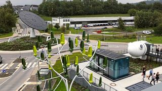 Der All Electric Society Park in Blomberg: Hinten links befindet sich im Kreisel das Erkennungszeichen, ein Solartracker mit einem Durchmesser von 12 Metern. Er lässt sich um die Zentralachse zur Sonne drehen, vorne im Bild steht ein Windenergieerzeuger in Baumform, rechts sieht man einen Cube und eine begehbare Windgondel.  (Bild: VCG/A. Unger-Leinhos)